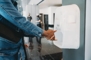 Eine Person desinfiziert sich die Hände an einem Steripower white edition Desinfektionsmittelspender.